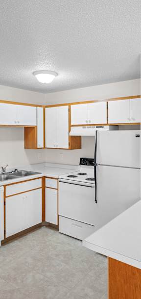 an empty kitchen with white appliances and wooden cabinets
