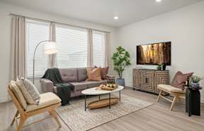 A living room with a grey couch, a wooden chair, a coffee table, and a painting on the wall.