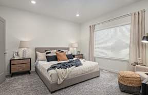 A bedroom with a large bed and a window with blinds.