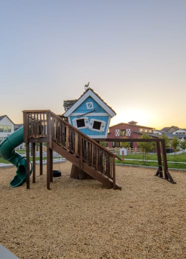 a playset with a slide and a tree house in front of houses