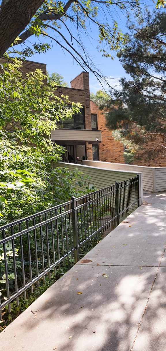 A walkway with a metal railing and trees on both sides.