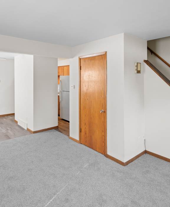 A room with a grey carpet and a wooden door.
