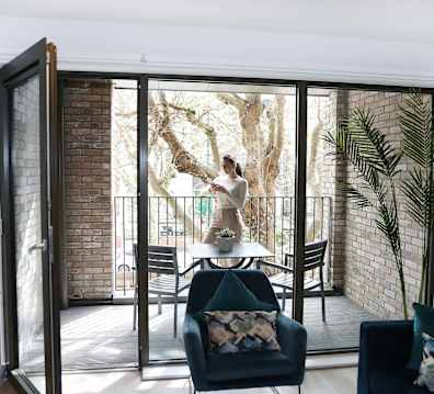 a woman standing on a balcony in front of sliding glass doors