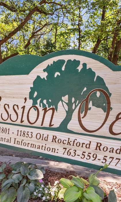 A sign for Mission Oaks with a tree logo and a phone number.
