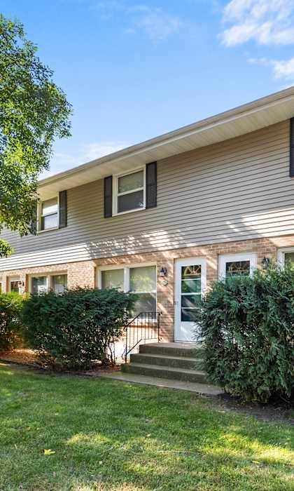 the front of a house with a lawn and shrubs