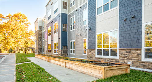 A modern building with a blue and grey exterior and a wooden planter box in front.