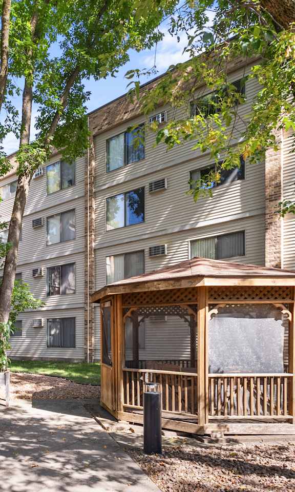 A gazebo sits in the middle of a courtyard between two apartment buildings.