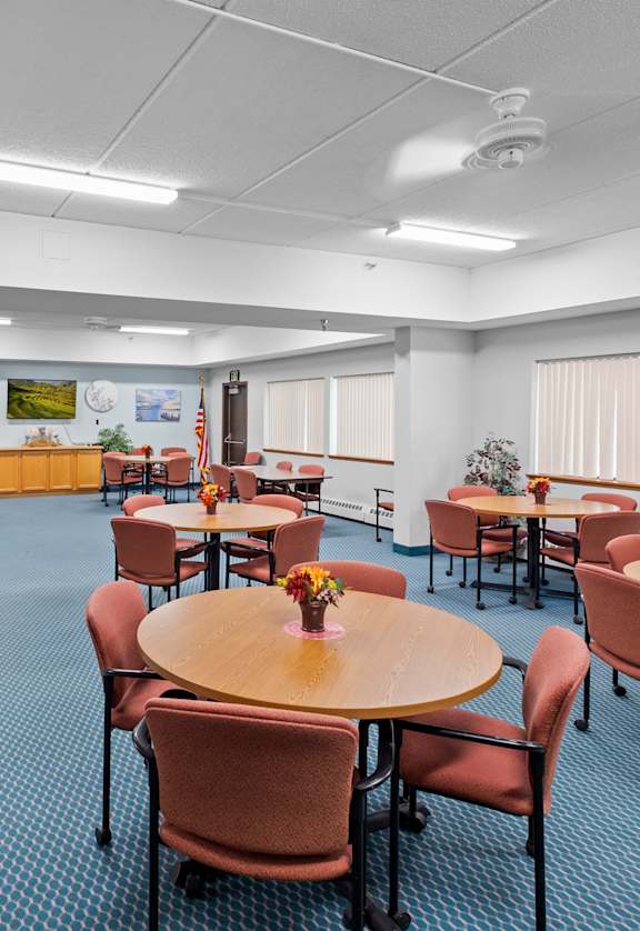 A room with tables and chairs and a blue carpet.