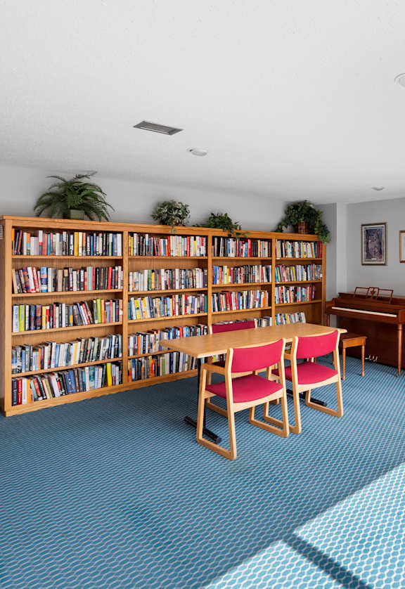 A room with a blue carpet and a bookshelf filled with books.