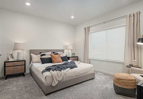 A bedroom with a large bed and a window with blinds.