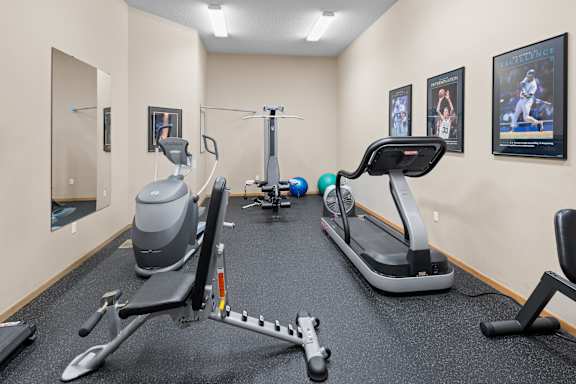 A gym with a treadmill, elliptical trainer, and other exercise equipment.