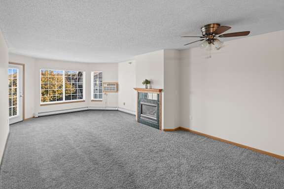A spacious living room with a fireplace and a ceiling fan.
