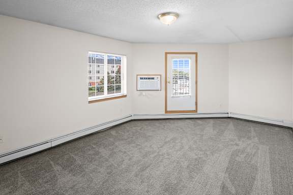A room with a carpeted floor, a window, and a door.