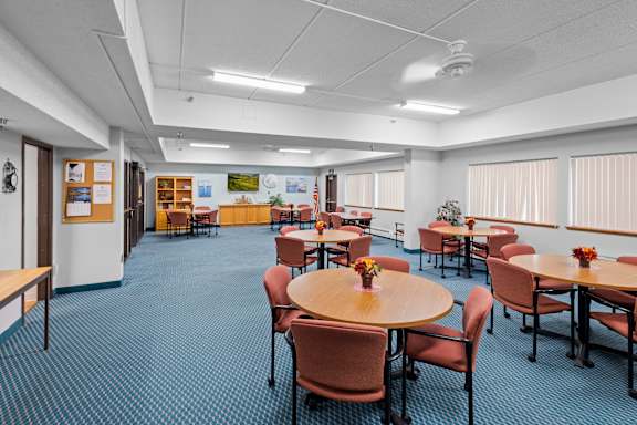 A room with tables and chairs and a blue carpet.
