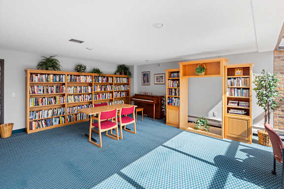 A room with a blue carpet and a bookshelf filled with books.