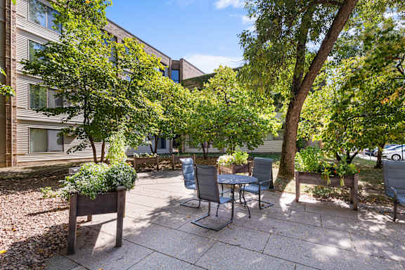 A patio with a table and chairs surrounded by trees.