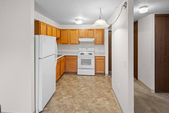 A kitchen with white appliances and wooden cabinets.