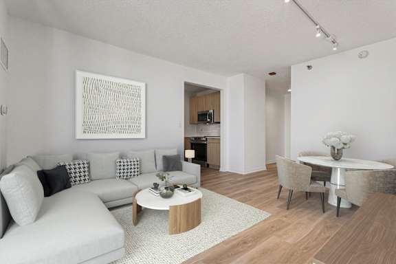A modern living room with a grey sofa, a coffee table, and a dining table set up.