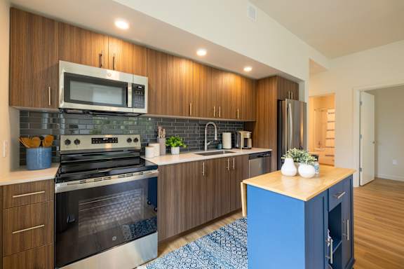 A kitchen with a blue island and stainless steel appliances.