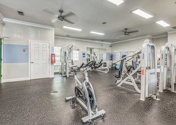 A gym with a variety of exercise equipment including treadmills, stationary bikes, and weight machines.