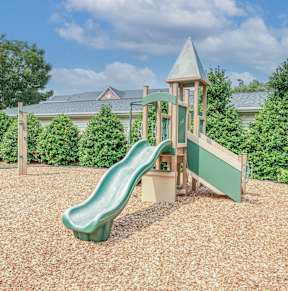A playground with a green slide and a wooden structure.