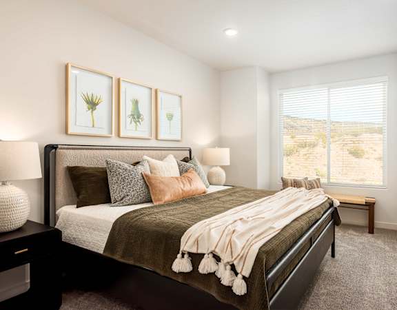 A bedroom with a large bed and a window overlooking a desert landscape.
