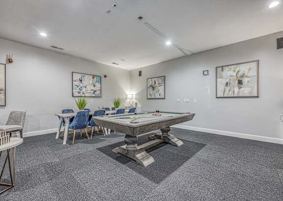A room with a pool table and chairs.