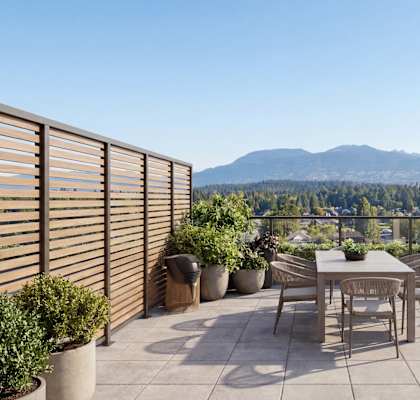 A patio with a table and chairs overlooking a mountain range.