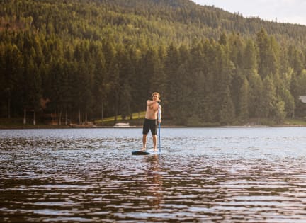 a man standing on a paddle board in a lake at Copestone, Idaho