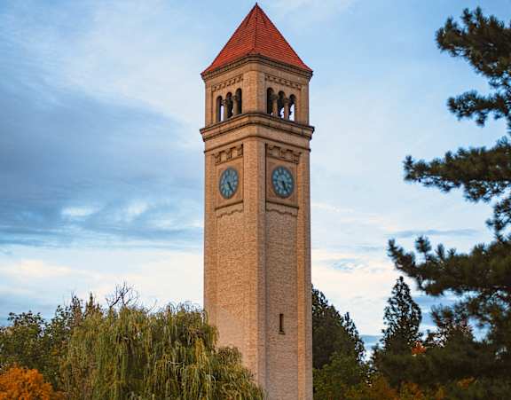 A tall clock tower with a red roof stands in front of a blue sky.