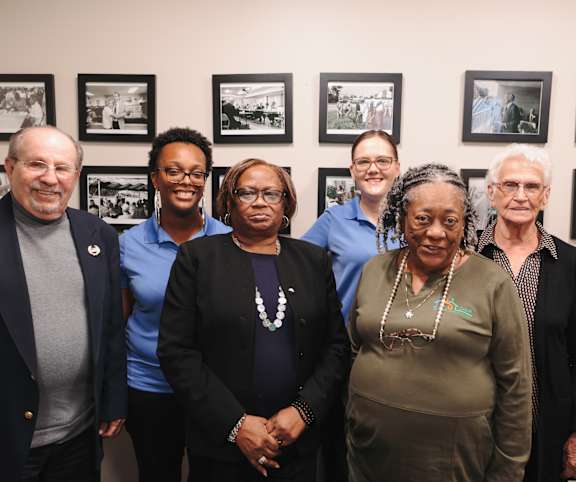 A group of people are standing in front of a wall with framed pictures.