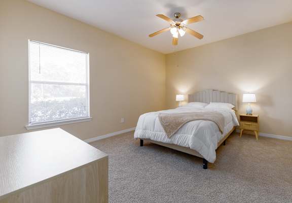 A bedroom with a bed, nightstand, and window.