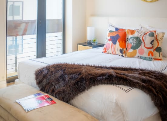 A bed with a white sheet and a brown throw is in the image.