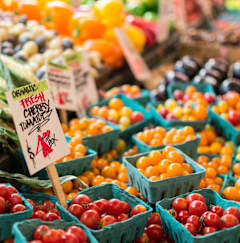 A sign in front of a pile of tomatoes says "Organic Trash Cherry".
