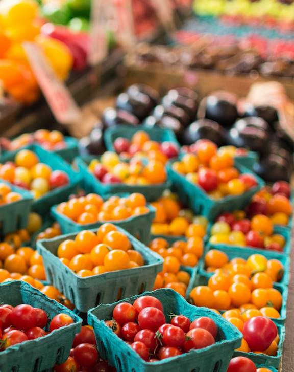 A sign in front of a pile of tomatoes says "Organic Trash Cherry".