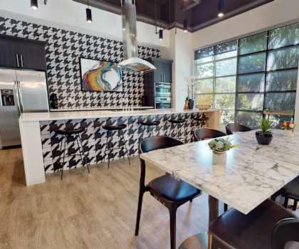 A modern kitchen with a marble table and black chairs.