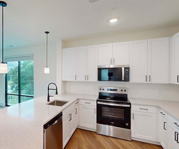 A modern kitchen with white cabinets and stainless steel appliances.