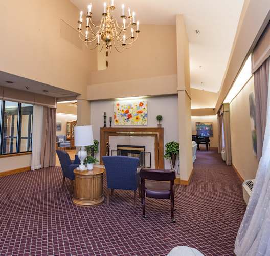 the lobby of a hotel with chairs and a fireplace at River Commons Senior Living, Redding