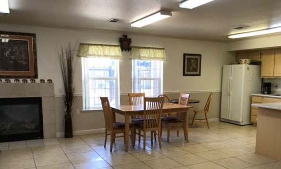 Image of fireplace, table, windows, and kitchen space