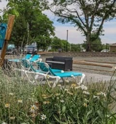 a group of lounge chairs sitting on the side of a train track