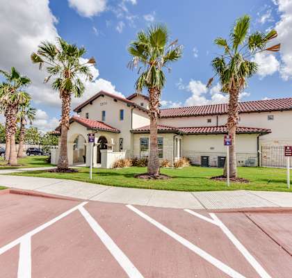 a building with palm trees in front of it and a parking lot