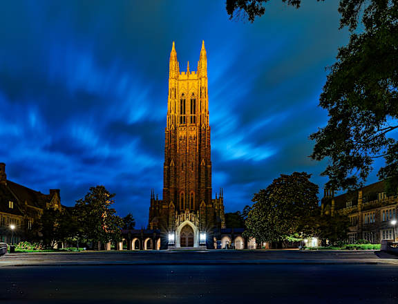 A tall tower stands in the center of a courtyard surrounded by buildings.