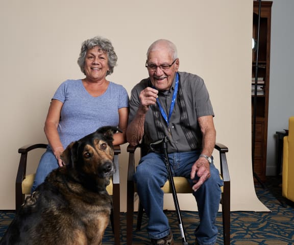 an older man and woman sitting in chairs with a dog