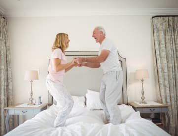 a man and a woman standing on a bed with their feet in the air