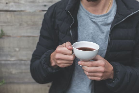 a man in a jacket holding a cup of coffee