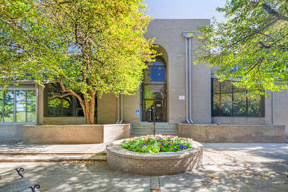 A building with a circular flower bed in front of it.