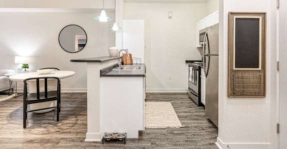 a living room with a kitchen and a dining area with a table and chairs