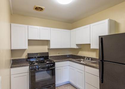 A kitchen with white cabinets and a black refrigerator.