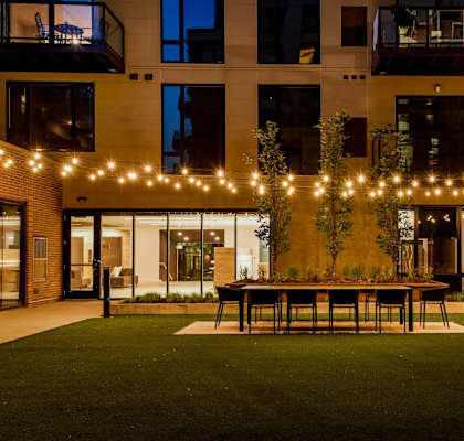 A patio with a table and chairs is surrounded by a building with balconies.