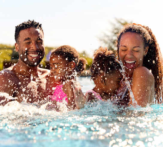A family of four is enjoying a swim in a pool.
